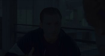 Movie still from “Something in the Air” (2012), directed by Olivier Assayas – A man is sitting in a dark room; Close Up shot, Over the shoulder angle
