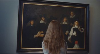 Movie still from “Something in the Air” (2012), directed by Olivier Assayas – A woman standing in front of a painting; Medium shot, Over the shoulder angle