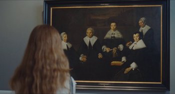 Movie still from “Something in the Air” (2012), directed by Olivier Assayas – A woman standing in front of a painting; Medium shot, Over the shoulder angle