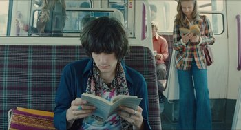 Movie still from “Something in the Air” (2012), directed by Olivier Assayas – A person sitting on a bus reading a book; Medium shot, Over the shoulder angle
