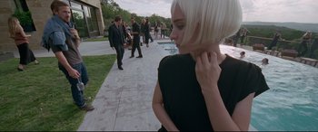 Movie still from “Song to Song” (2017), directed by Terrence Malick – A woman in a black dress standing next to a pool; Medium shot, Low angle