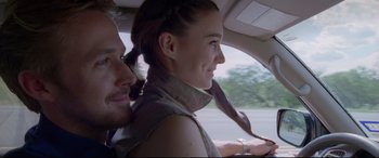 Movie still from “Song to Song” (2017), directed by Terrence Malick – A man and a woman driving a car on a road; Close Up shot, Over the shoulder angle