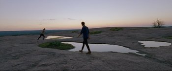 Movie still from “Song to Song” (2017), directed by Terrence Malick – A man is walking on the rocks by the water; Extreme Wide shot, High angle