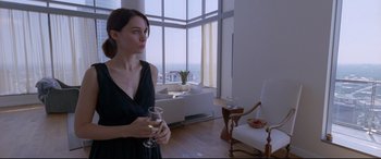 Movie still from “Song to Song” (2017), directed by Terrence Malick – A woman holding a glass of wine in a living room; Medium shot, Over the shoulder angle
