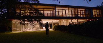 Movie still from “Song to Song” (2017), directed by Terrence Malick – A person standing in front of a house at night; Extreme Wide shot, Low angle