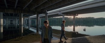 Movie still from “Song to Song” (2017), directed by Terrence Malick – A man and a woman walking under a bridge; Wide shot, Low angle
