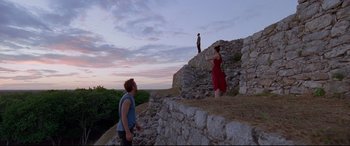 Movie still from “Song to Song” (2017), directed by Terrence Malick – Two people standing on a stone wall near a hill; Extreme Wide shot, Low angle