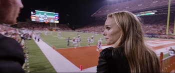 Movie still from “Song to Song” (2017), directed by Terrence Malick – A woman standing on a football field watching a football game; Close Up shot, Over the shoulder angle