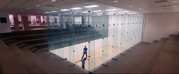 Movie still from “Song to Song” (2017), directed by Terrence Malick – A man standing in front of a racquetball court with rackets; Extreme Wide shot, Low angle