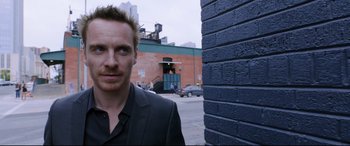 Movie still from “Song to Song” (2017), directed by Terrence Malick – A man standing next to a brick building; Close Up shot, Over the shoulder angle