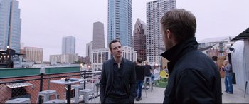 Movie still from “Song to Song” (2017), directed by Terrence Malick – A man standing on a deck talking to another man in a suit; Medium shot, Over the shoulder angle