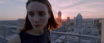 Movie still from “Song to Song” (2017), directed by Terrence Malick – A woman standing in front of a city at sunset; Close Up shot, Low angle