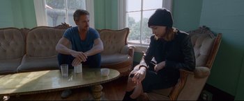 Movie still from “Song to Song” (2017), directed by Terrence Malick – A man and a woman sitting in a living room next to each other; Medium shot, Over the shoulder angle
