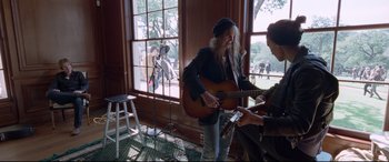 Movie still from “Song to Song” (2017), directed by Terrence Malick – A man holding a guitar in front of another man; Medium shot, Low angle