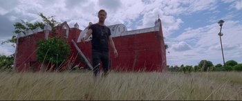 Movie still from “Song to Song” (2017), directed by Terrence Malick – A man standing in a field holding a baseball bat; Wide shot, Low angle