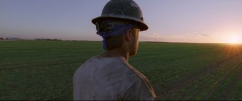 Movie still from “Song to Song” (2017), directed by Terrence Malick – A man wearing a hard hat in the middle of a field; Wide shot, Low angle