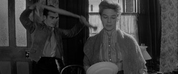 Movie still from “Sons and Lovers” (1960), directed by Jack Cardiff – A woman holding a white plate in front of a man; Medium shot, Over the shoulder angle