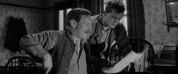 Movie still from “Sons and Lovers” (1960), directed by Jack Cardiff – Two men looking at a piece of paper together; Medium shot, Low angle