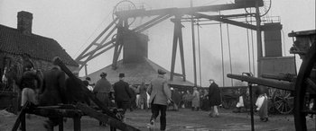 Movie still from “Sons and Lovers” (1960), directed by Jack Cardiff – A group of people walking near a large structure; Extreme Wide shot, High angle