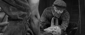 Movie still from “Sons and Lovers” (1960), directed by Jack Cardiff – A man laying on the ground next to another man; Medium shot, High angle