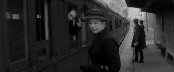 Movie still from “Sons and Lovers” (1960), directed by Jack Cardiff – A woman wearing a hat standing next to a train; Medium shot, Low angle