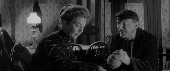 Movie still from “Sons and Lovers” (1960), directed by Jack Cardiff – An old photo of two people sitting at a table; Medium shot, Over the shoulder angle