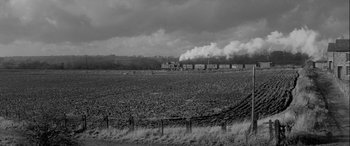 Movie still from “Sons and Lovers” (1960), directed by Jack Cardiff – A train traveling down tracks through a field; Extreme Wide shot, Low angle