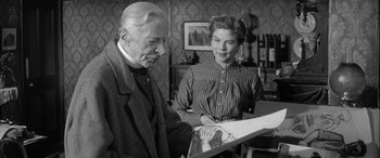 Movie still from “Sons and Lovers” (1960), directed by Jack Cardiff – An older man and a younger woman look at a piece of paper; Medium shot, Over the shoulder angle