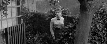 Movie still from “Sons and Lovers” (1960), directed by Jack Cardiff – A woman standing next to a brick wall; Medium shot, Over the shoulder angle