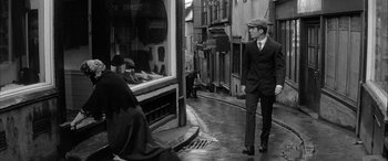 Movie still from “Sons and Lovers” (1960), directed by Jack Cardiff – A black and white photo of a man walking down the street; Wide shot, Over the shoulder angle