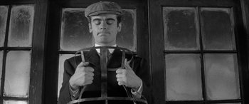 Movie still from “Sons and Lovers” (1960), directed by Jack Cardiff – A black and white photo of a man holding a tie; Medium shot, Overhead angle