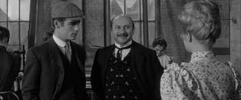 Movie still from “Sons and Lovers” (1960), directed by Jack Cardiff – A man with a mustache wearing a suit and tie; Medium shot, Over the shoulder angle