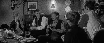 Movie still from “Sons and Lovers” (1960), directed by Jack Cardiff – A group of men and women sitting around a table; Medium shot, Over the shoulder angle