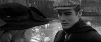 Movie still from “Sons and Lovers” (1960), directed by Jack Cardiff – A young man wearing a hat and a tie standing in front of a flock of swans; Close Up shot, Over the shoulder angle