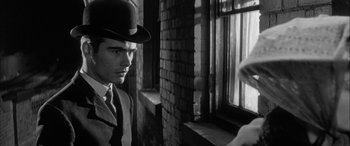 Movie still from “Sons and Lovers” (1960), directed by Jack Cardiff – A black and white photo of a man in a suit and a hat; Close Up shot, Over the shoulder angle