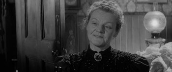 Movie still from “Sons and Lovers” (1960), directed by Jack Cardiff – An older woman wearing a black dress and a necklace; Close Up shot, Over the shoulder angle