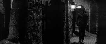 Movie still from “Sons and Lovers” (1960), directed by Jack Cardiff – A brick wall with a light on in the middle of it; Wide shot, High angle