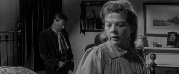 Movie still from “Sons and Lovers” (1960), directed by Jack Cardiff – A man and a woman standing in front of a shelf; Medium shot, Over the shoulder angle