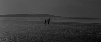 Movie still from “Sons and Lovers” (1960), directed by Jack Cardiff – Two people holding hands on the beach at night; Extreme Wide shot, High angle