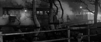 Movie still from “Sons and Lovers” (1960), directed by Jack Cardiff – A man standing next to a tree near a fence; Extreme Wide shot, Over the shoulder angle
