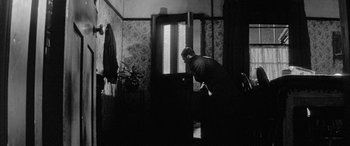 Movie still from “Sons and Lovers” (1960), directed by Jack Cardiff – A man standing in front of an open door in a room; Wide shot, Low angle