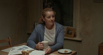 Movie still from “Sorry We Missed You” (2019), directed by Ken Loach – A woman sitting at a table holding a coffee mug; Medium shot, Over the shoulder angle