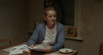 Movie still from “Sorry We Missed You” (2019), directed by Ken Loach – A woman sitting at a table with a plate of food; Medium shot, Over the shoulder angle