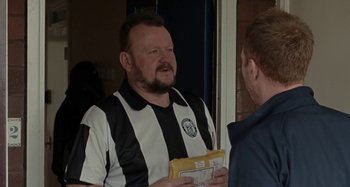 Movie still from “Sorry We Missed You” (2019), directed by Ken Loach – A man in a referee shirt holding a folder; Medium shot, Over the shoulder angle