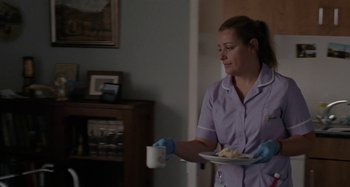 Movie still from “Sorry We Missed You” (2019), directed by Ken Loach – A woman holding a cup and a plate of food in a room; Medium shot, Over the shoulder angle