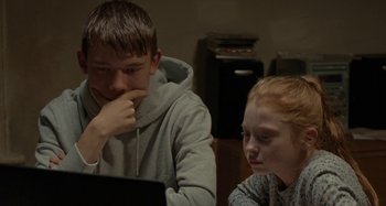 Movie still from “Sorry We Missed You” (2019), directed by Ken Loach – A boy and a girl are looking at a laptop; Medium shot, Over the shoulder angle