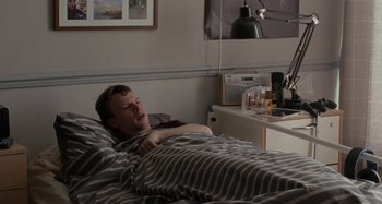 Movie still from “Sorry We Missed You” (2019), directed by Ken Loach – A man laying in a bed in a room; Medium shot, High angle