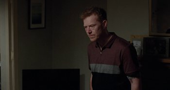 Movie still from “Sorry We Missed You” (2019), directed by Ken Loach – A man standing in a dark room looking down at the floor; Medium shot, Over the shoulder angle