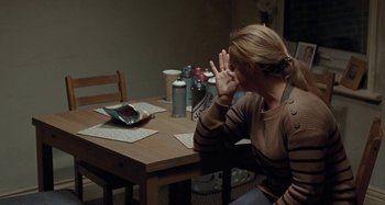 Movie still from “Sorry We Missed You” (2019), directed by Ken Loach – A woman sitting at a table in front of an empty wallet; Medium shot, High angle