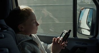 Movie still from “Sorry We Missed You” (2019), directed by Ken Loach – A young girl sitting in a car looking at her cell phone; Close Up shot, High angle